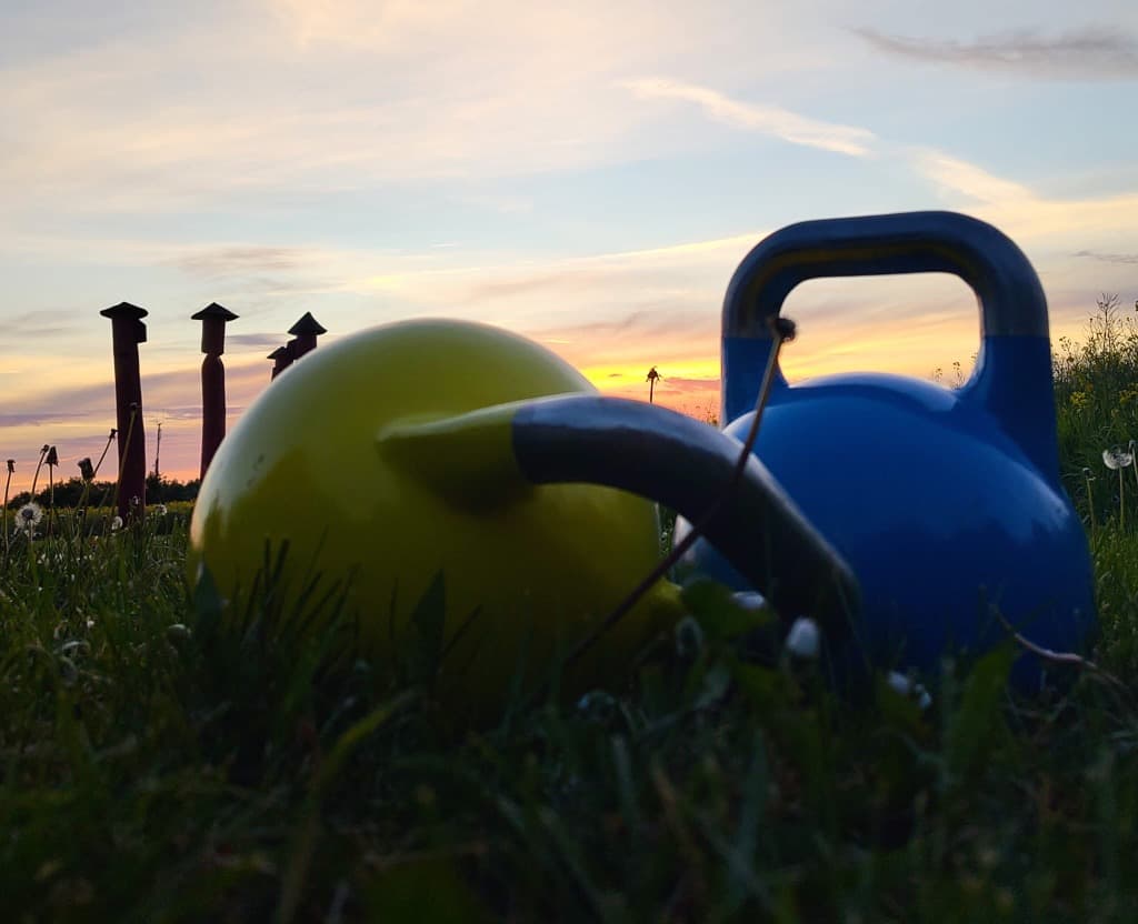 Kettlebells bei Sonnenuntergang im Gras